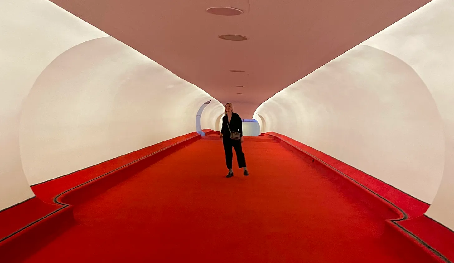 A figure walking through a red and white curved tunnel.